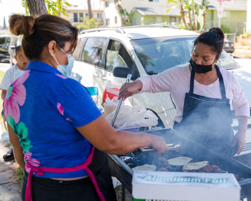 Two sisters cook tacos over a grill