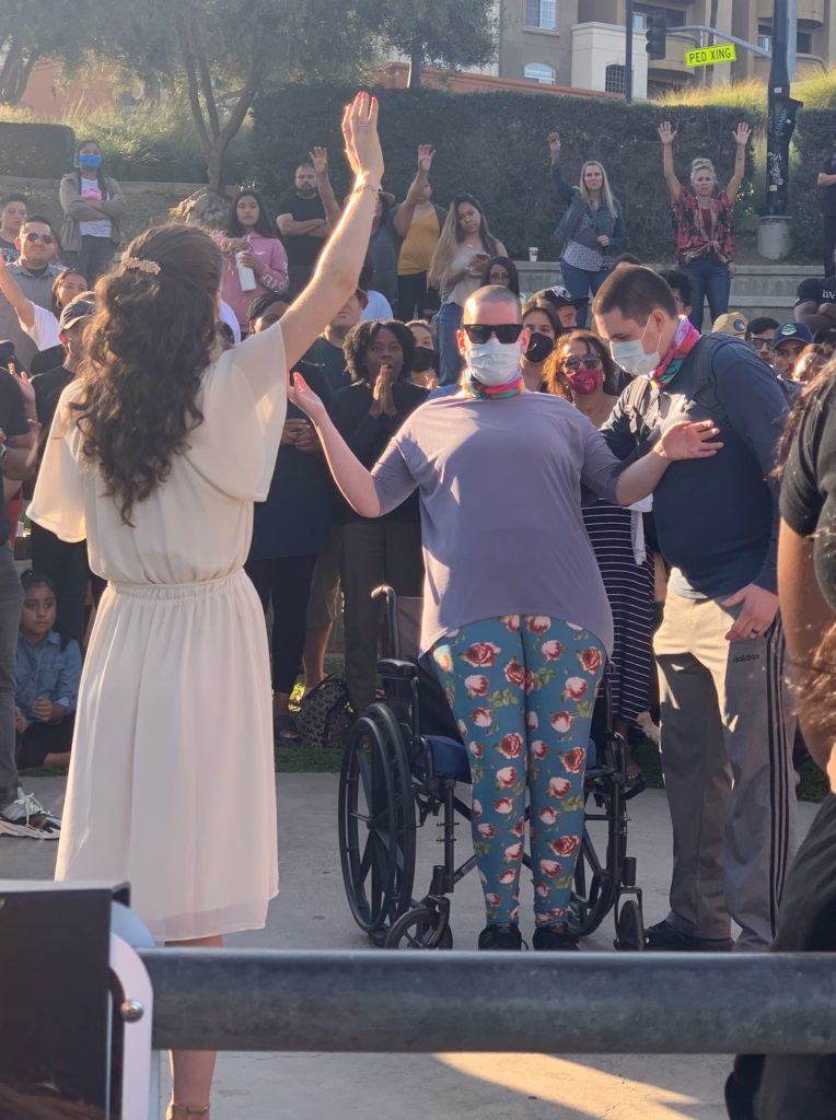 A woman stands up from her wheelchair during an open air session of Kathryn Krick's ministry.